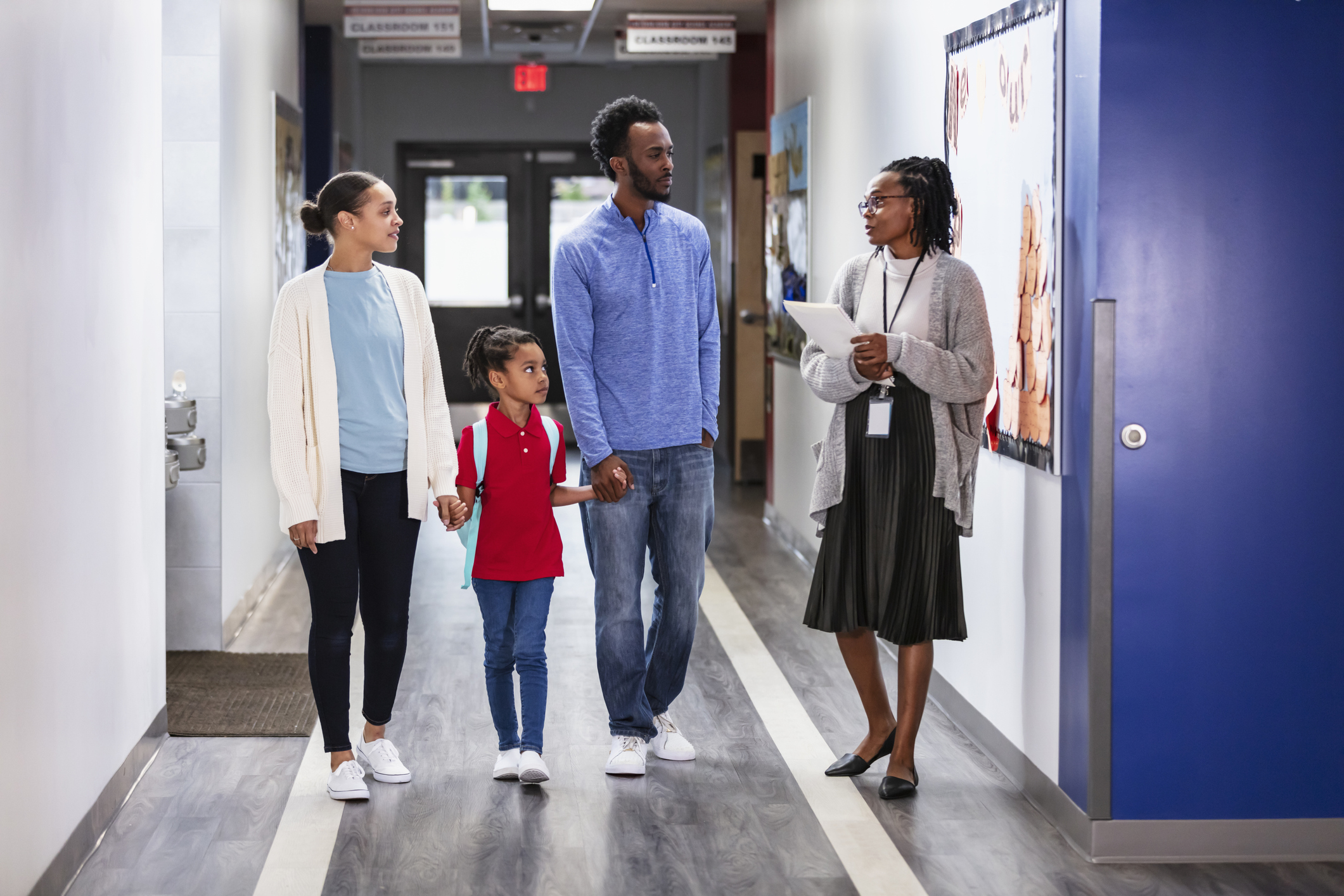 Une famille accompagnée par une agente école-famille-communauté dans les corridors de l'école.